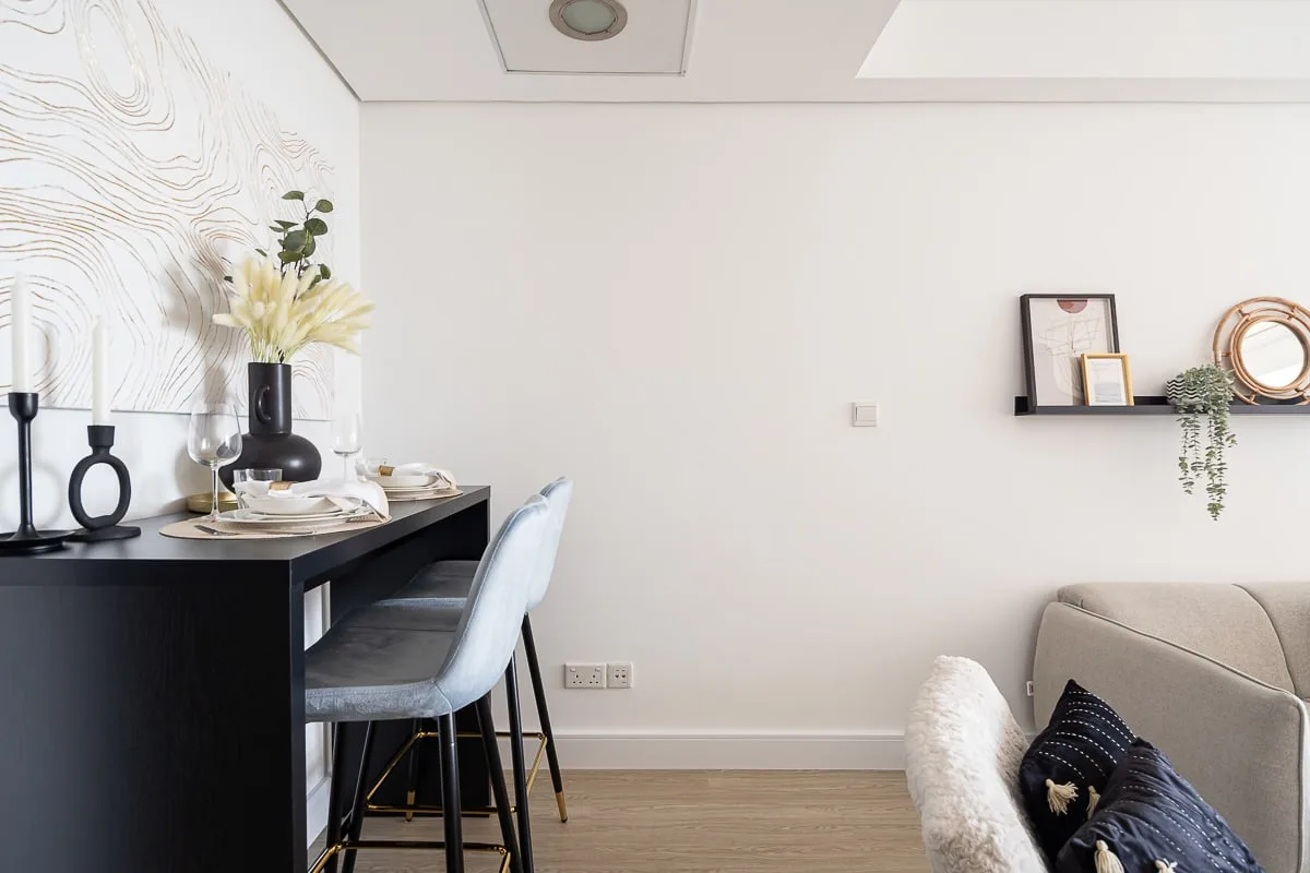 Comedor con una mesa oscura, asientos tapizados y flores decorativas.