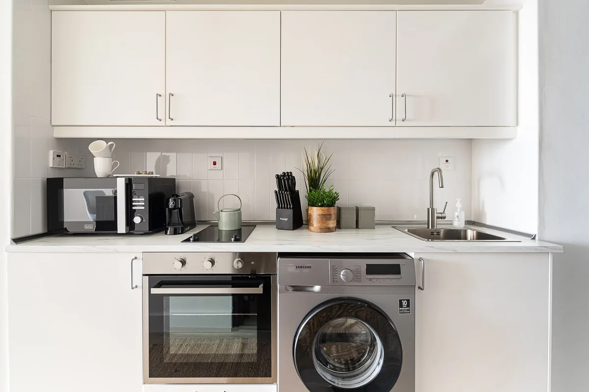 Una cocina luminosa con gabinetes blancos, una encimera y electrodomésticos integrados.