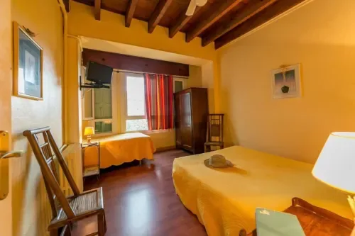 Yellow guest room with two beds and wooden beams.