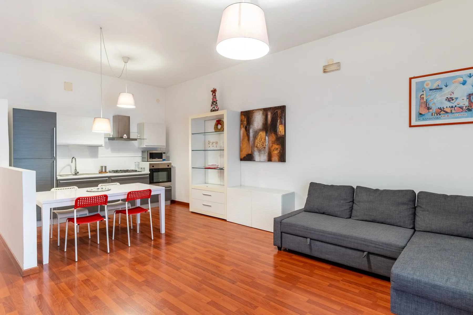 A bright open-plan living and dining area with a kitchen and gray seating.