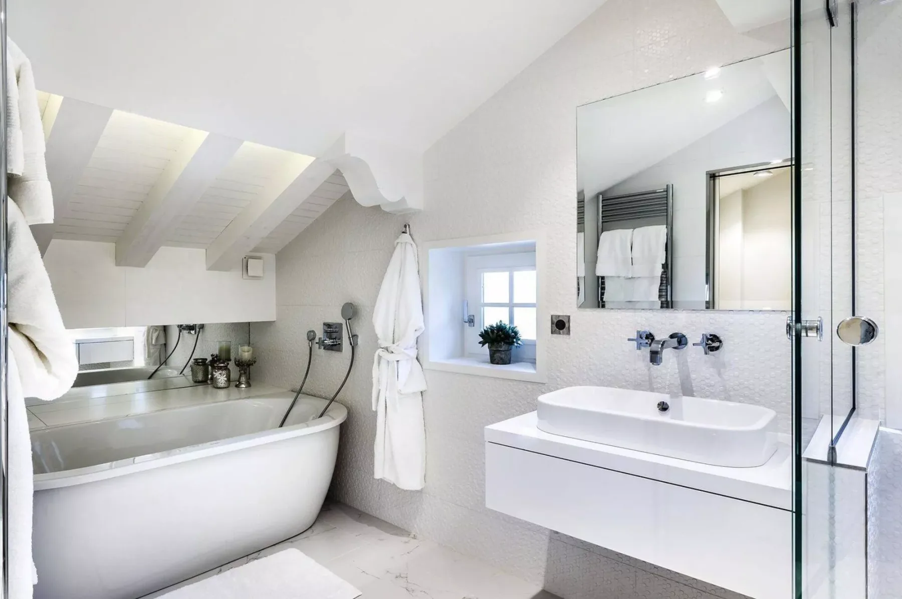 Un baño luminoso con bañera, lavabo y un espejo grande.