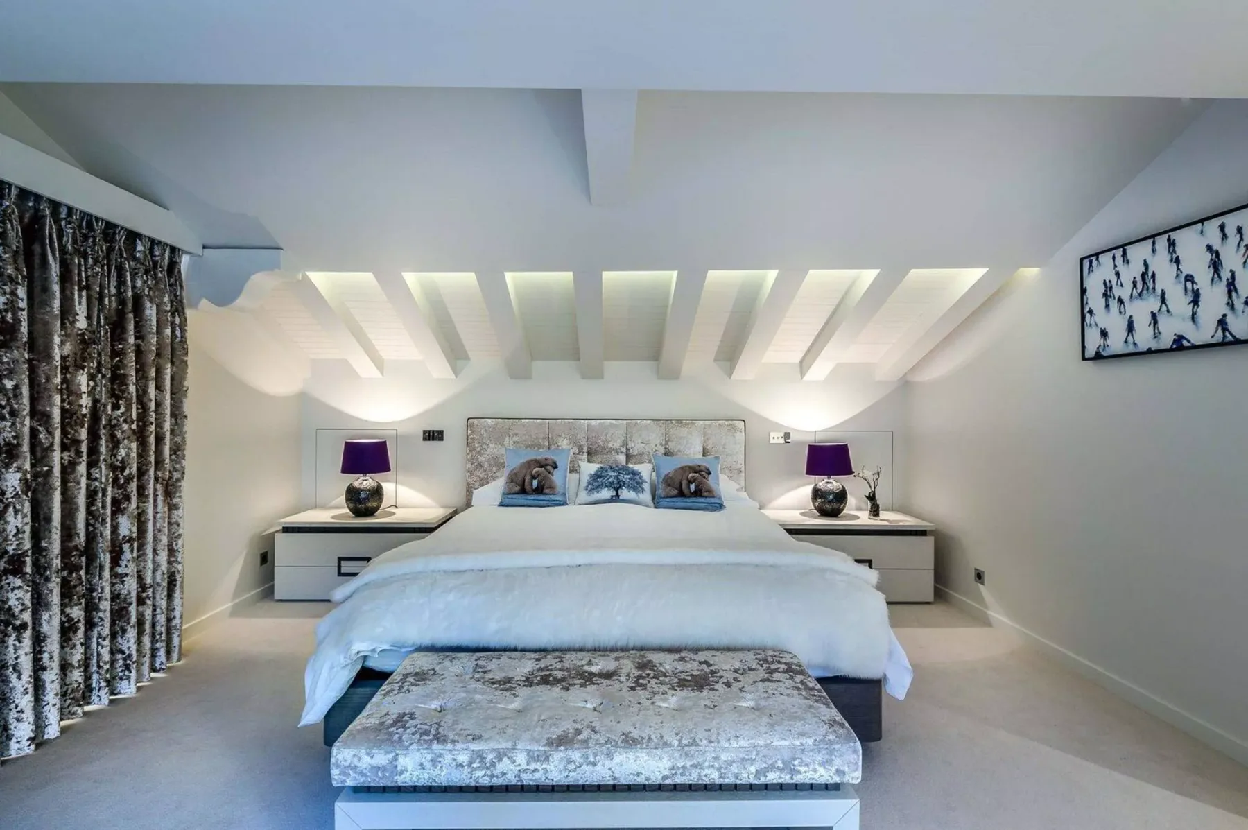 Un dormitorio luminoso con una cama grande, mesitas a ambos lados y cortinas estampadas.