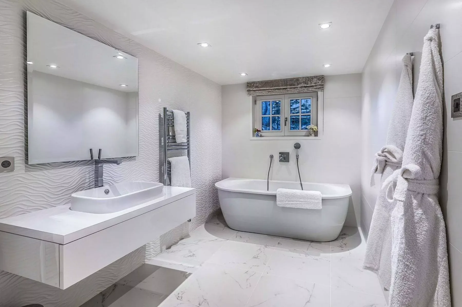 Un baño luminoso con bañera, lavabo y espejo de pared.