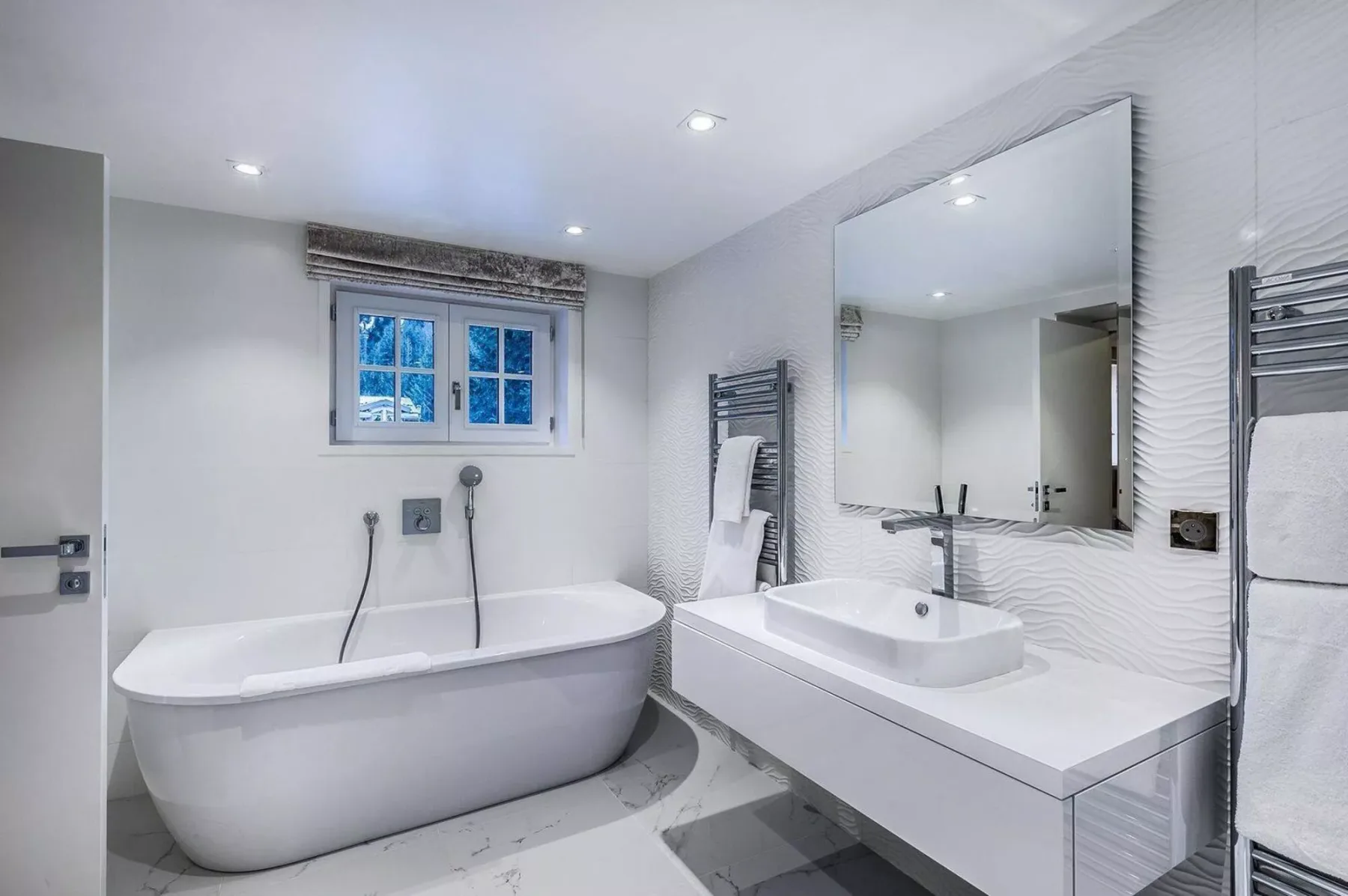 Un baño luminoso con una bañera exenta y un amplio tocador.