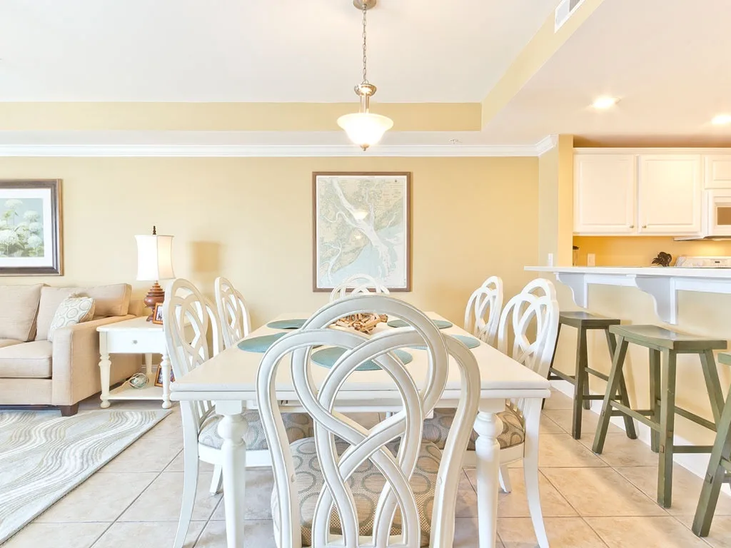 A bright dining area with a white table and chairs beside an open kitchen.