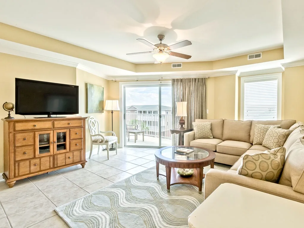 A bright living room with seating, a television, and sliding glass doors.