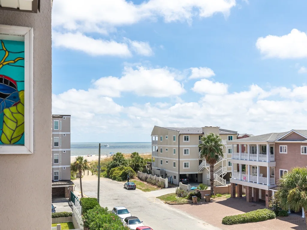 A coastal street with apartment buildings and the ocean visible beyond.