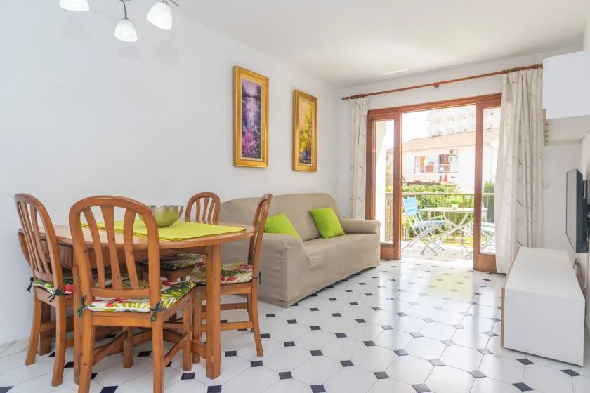 A bright living and dining area has a table, seating, and a glass door to the balcony.