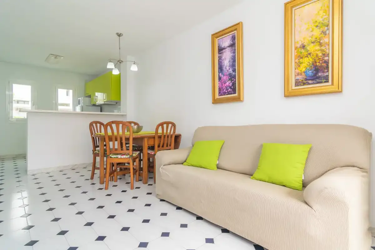 A living and dining area with a beige sofa and wooden dining table.