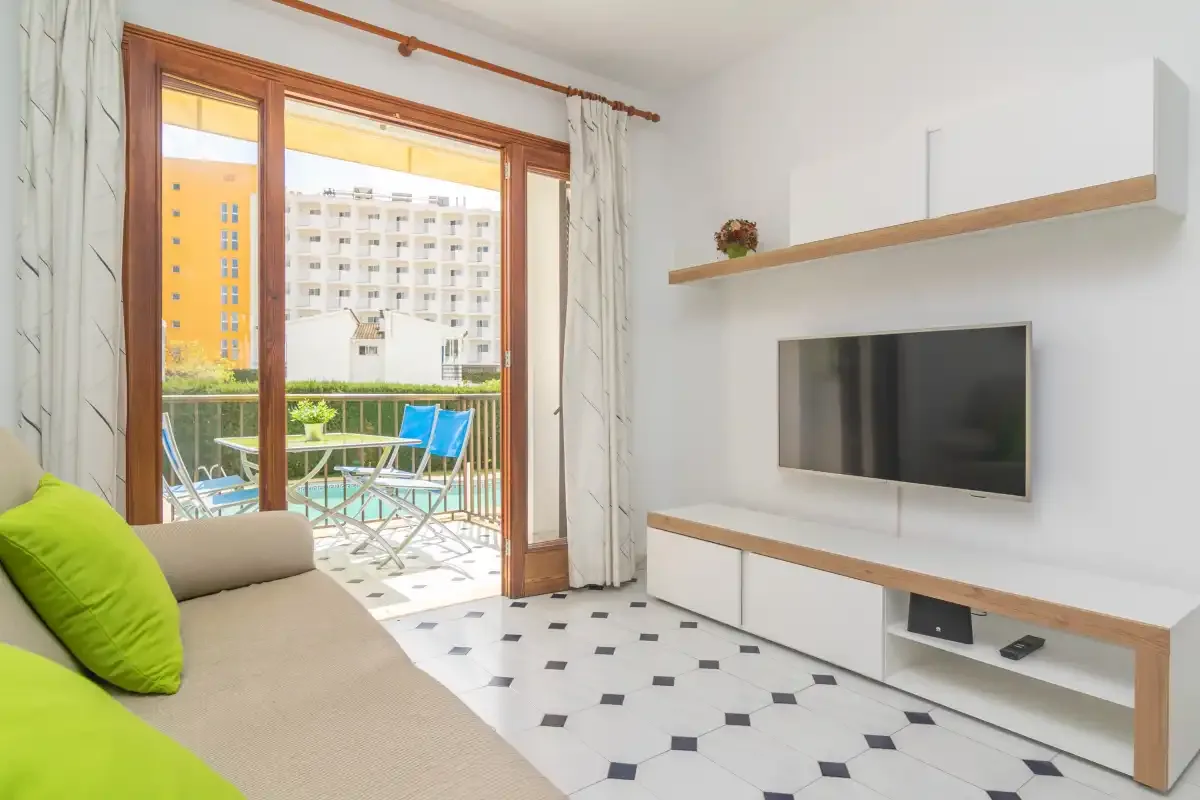 Living room with a television and an open glass door leading to a balcony.