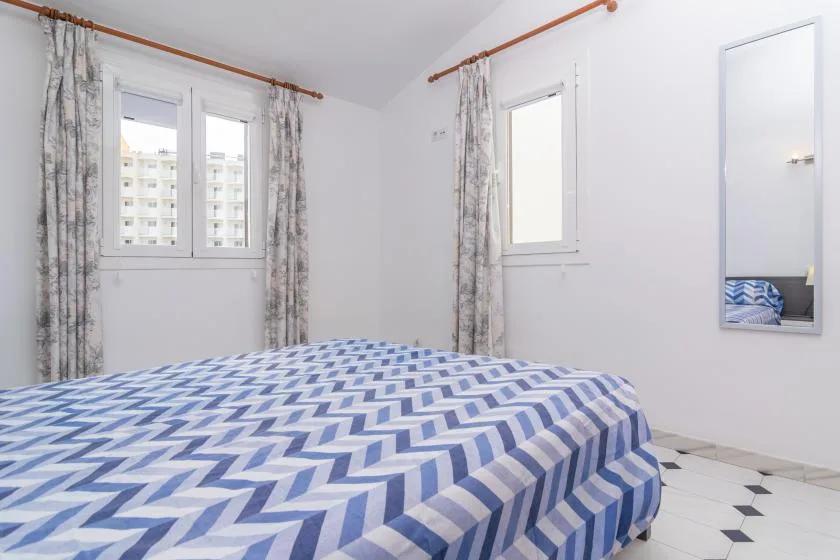 A bedroom with blue-and-white patterned bedding and curtained windows.