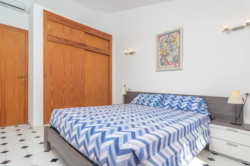 A bedroom with a bed covered in blue and white patterned bedding.