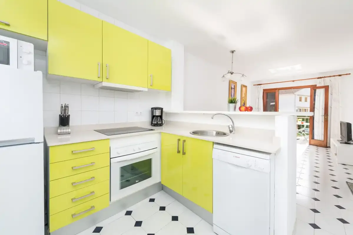 A bright kitchen with yellow cabinets and a white countertop.