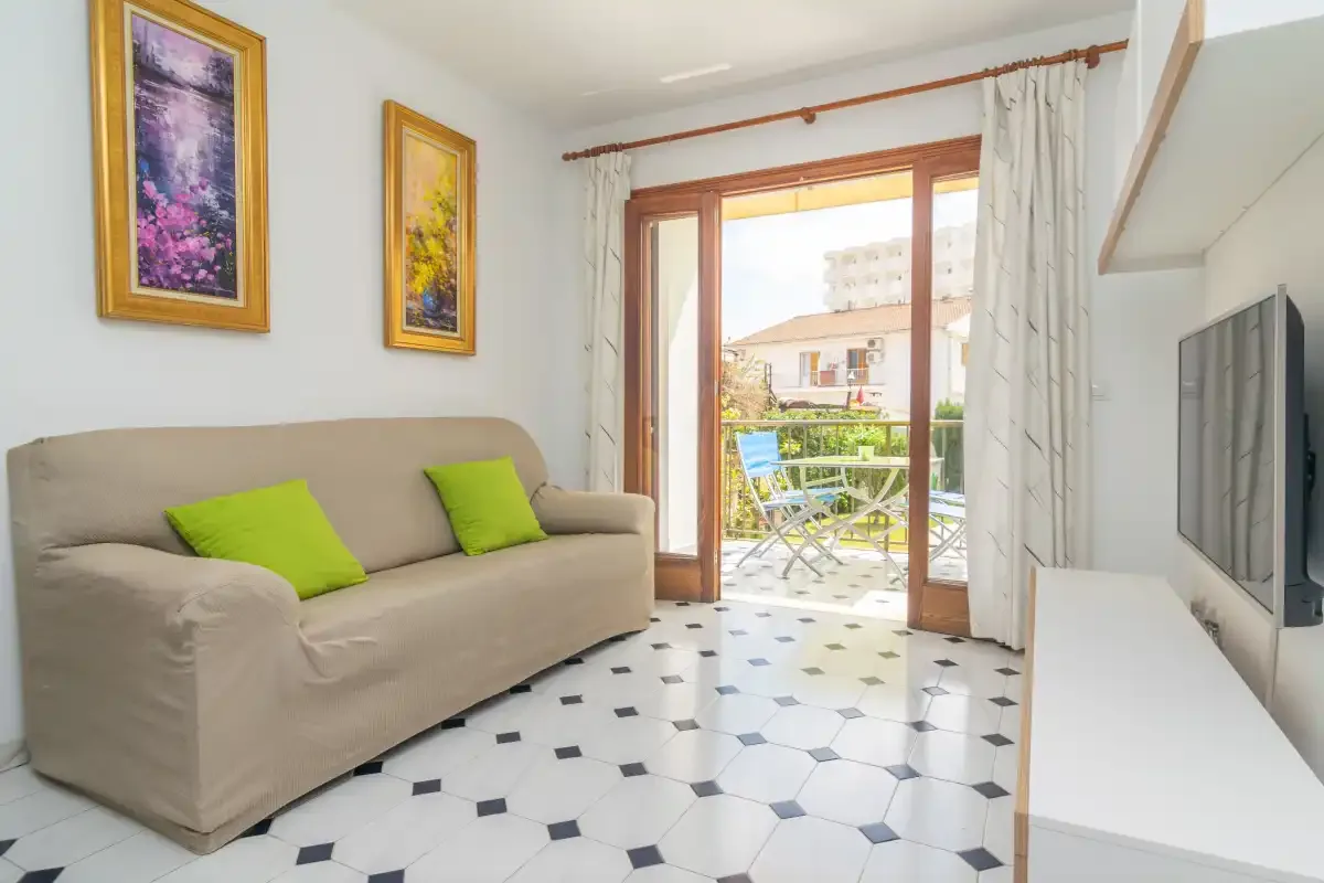 A living room with seating, framed artwork, and glass doors opening to a balcony.
