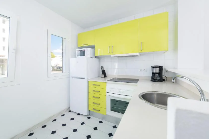 A bright kitchen with yellow cabinets, a refrigerator, and a sink.
