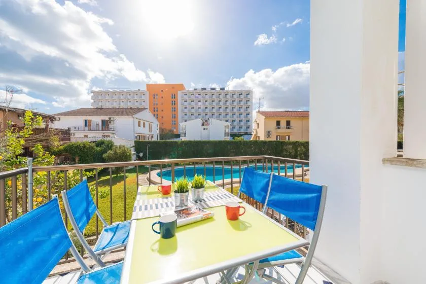 A balcony dining area overlooks a swimming pool and surrounding buildings.