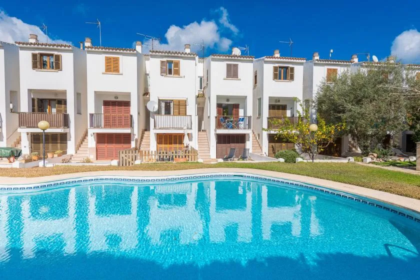 A swimming pool in front of a row of white residential buildings.