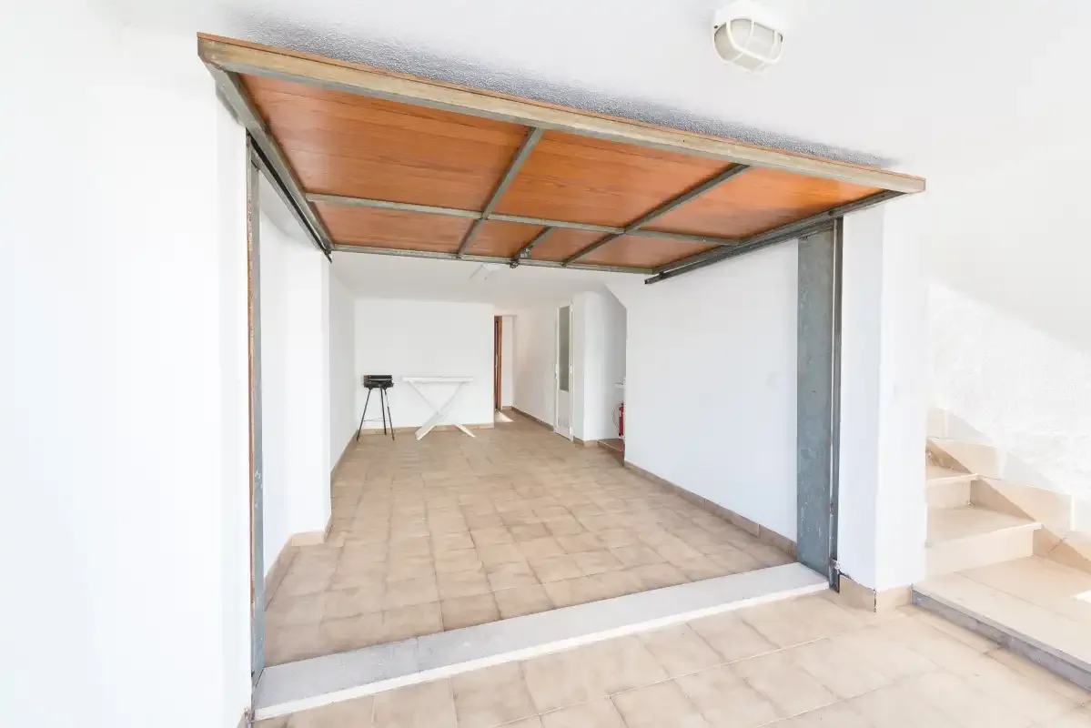 A covered garage with a tiled floor and an open entrance.