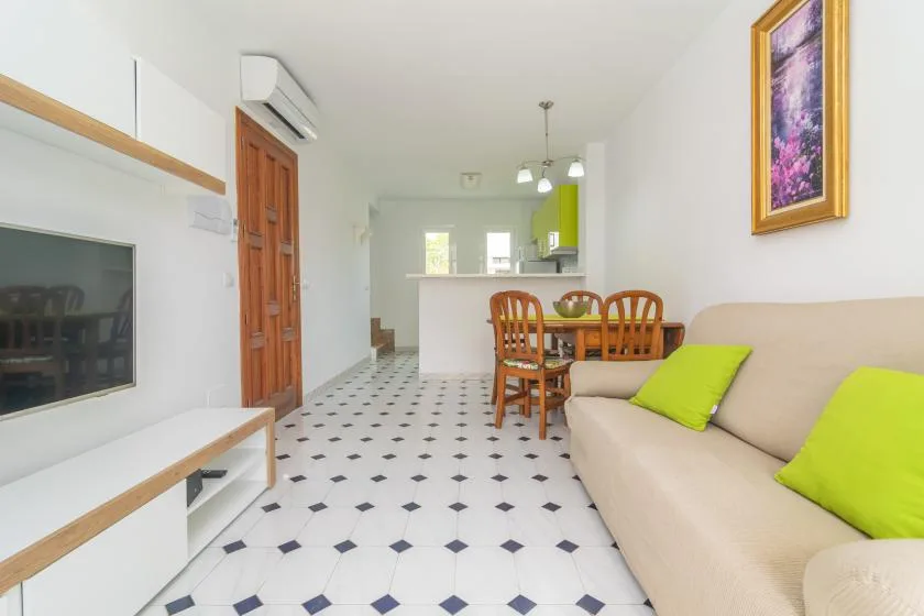 A bright living and dining area with a television, table, and seating.