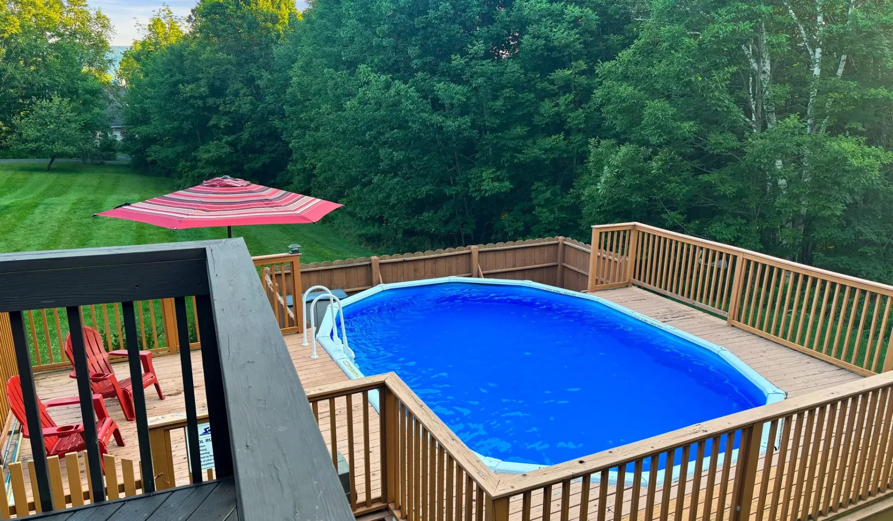 Una piscina al aire libre está rodeada por una terraza y barandilla de madera.