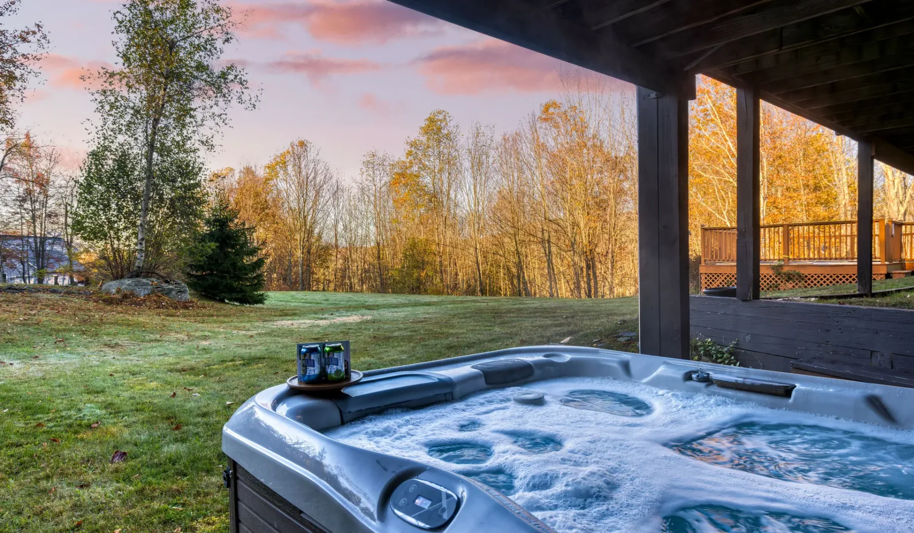 Un jacuzzi exterior está junto a una terraza cubierta con vistas a un patio de césped.