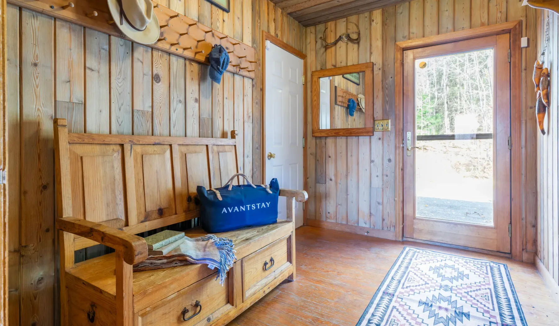 Una entrada revestida de madera con un banco de madera y una puerta acristalada.