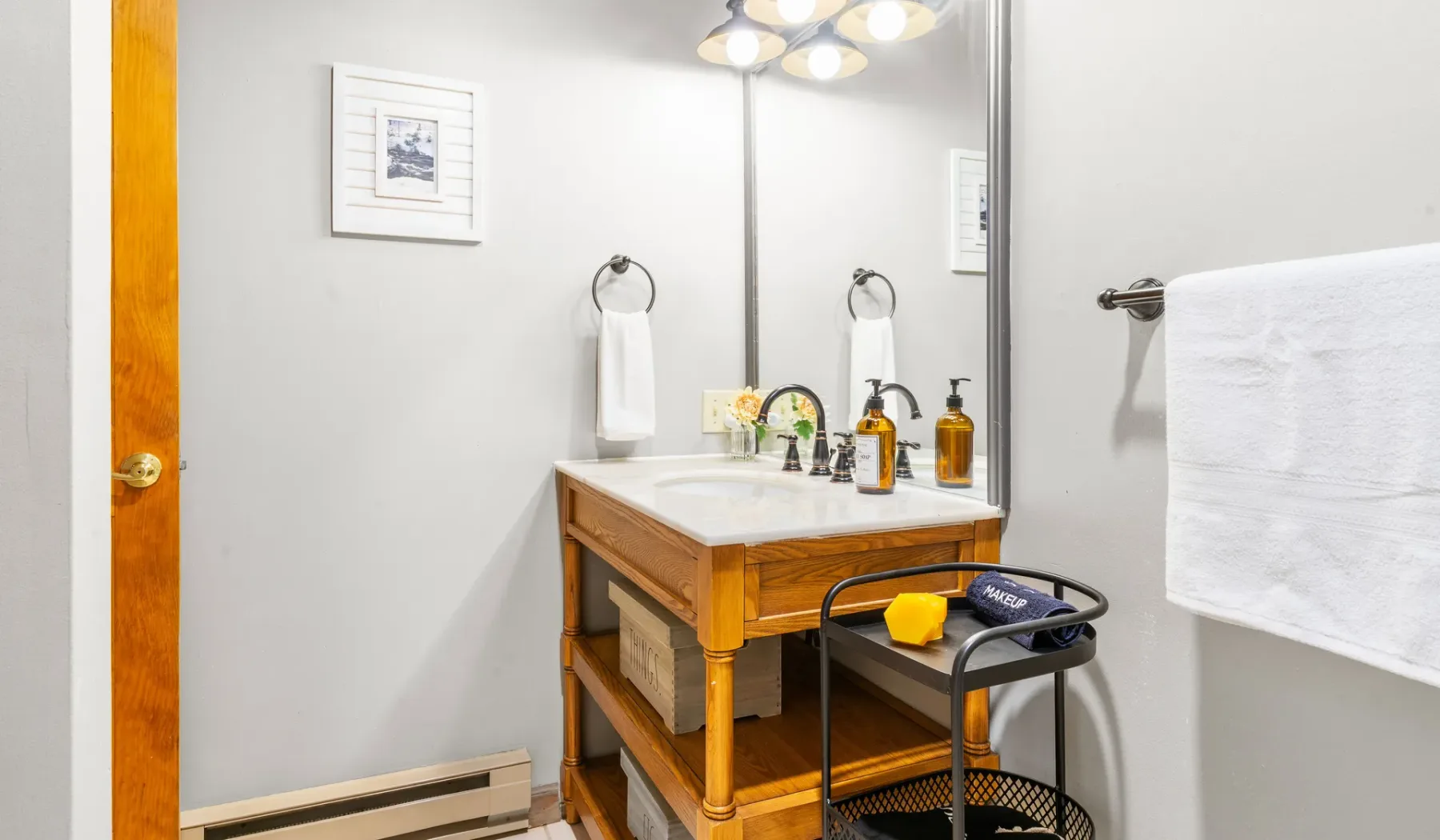 Un baño luminoso con un tocador de madera y un espejo grande.