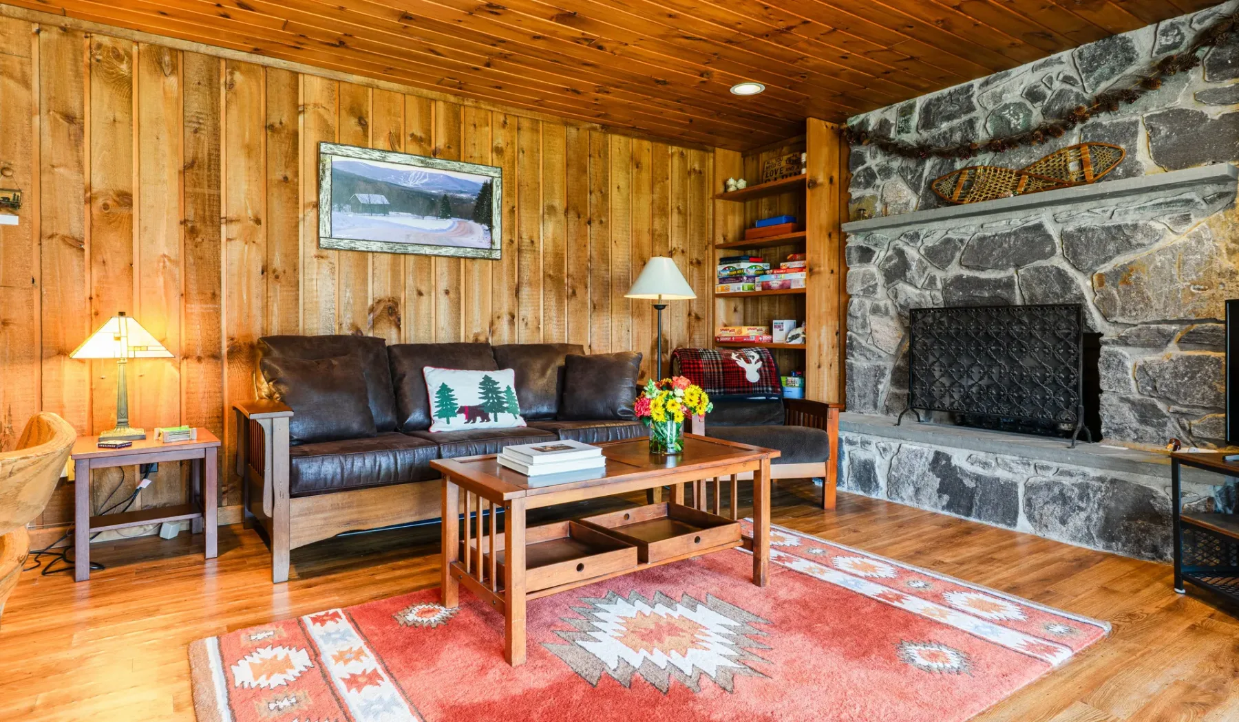 Una sala con paneles de madera, asientos, una mesa de centro y una chimenea de piedra.