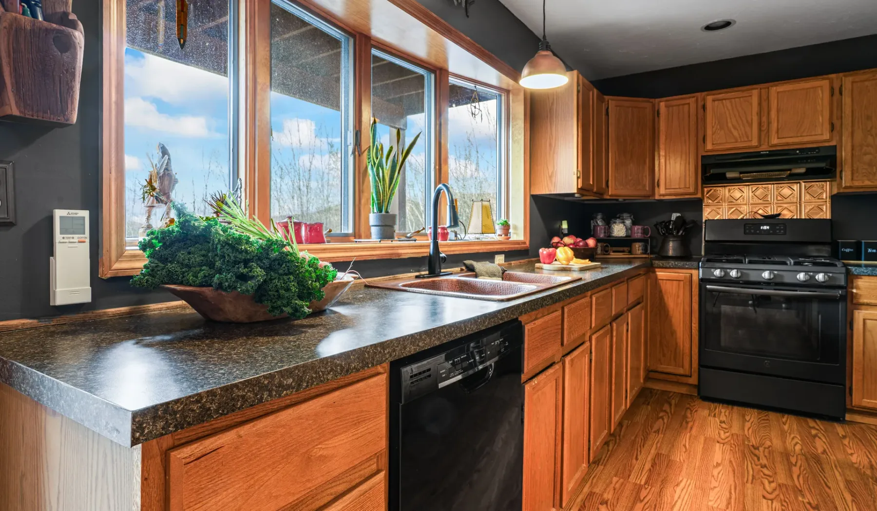 Una cocina con gabinetes de madera, una encimera y grandes ventanas.