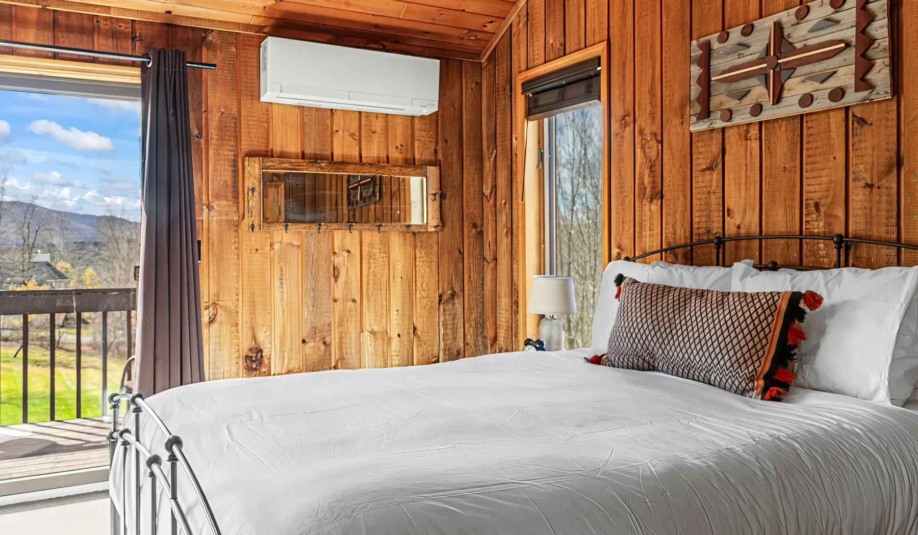 Un dormitorio con una cama blanca y paredes revestidas de madera junto a un balcón.