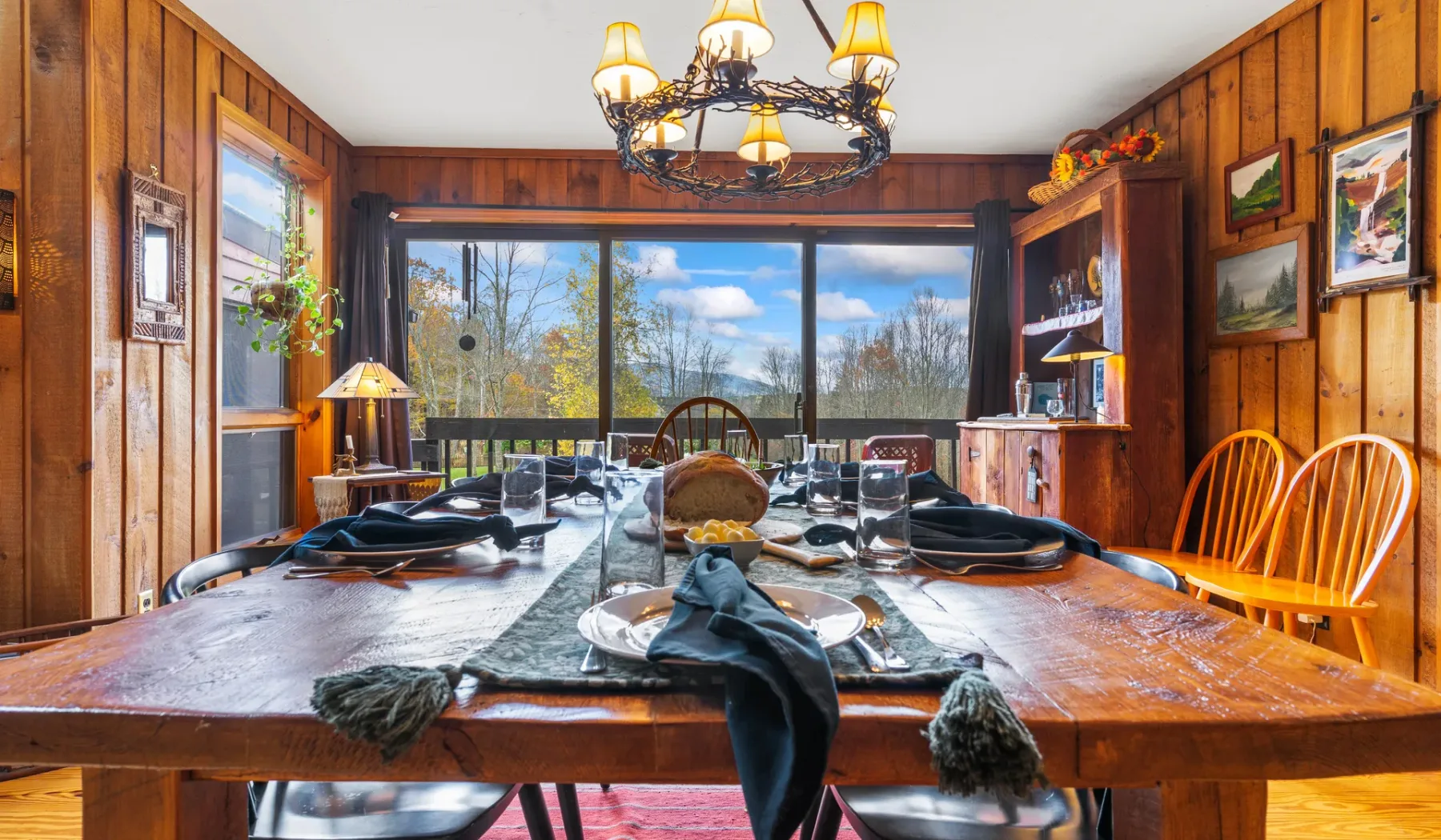 Un comedor revestido de madera, con una mesa larga frente a grandes ventanas.