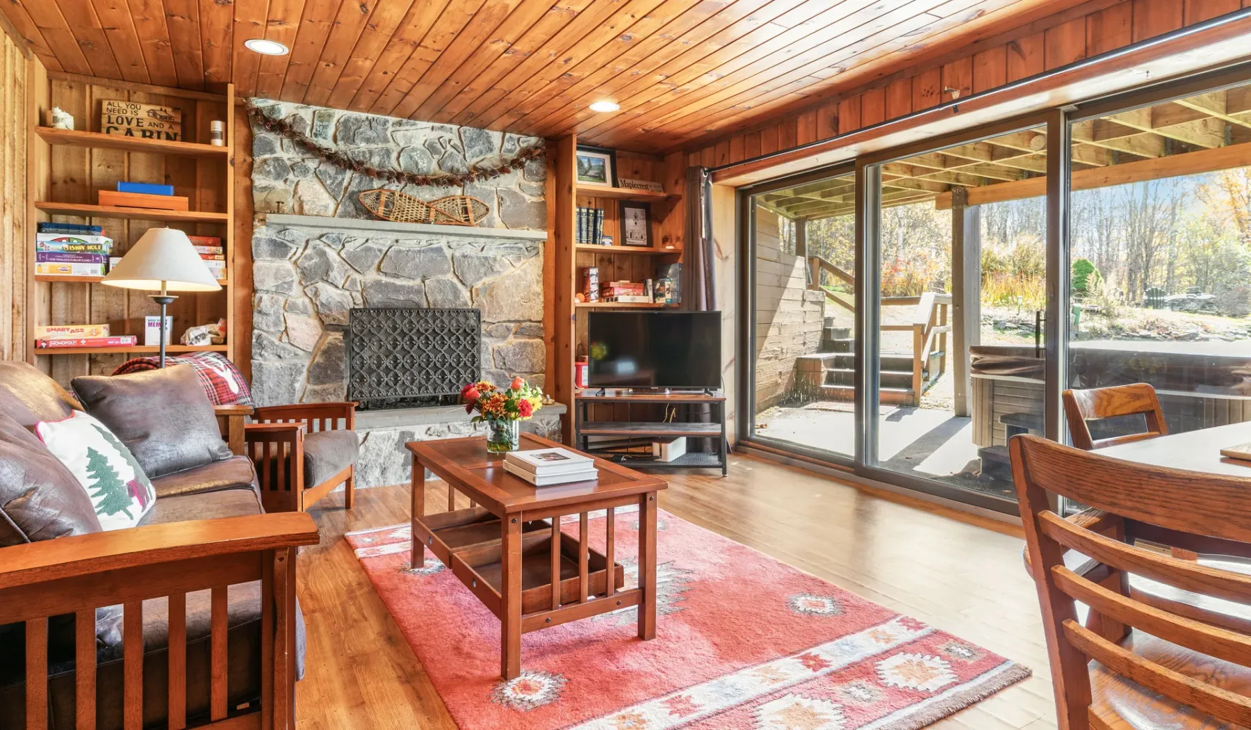 Una sala de estar revestida de madera, con chimenea de piedra y puertas corredizas de vidrio.