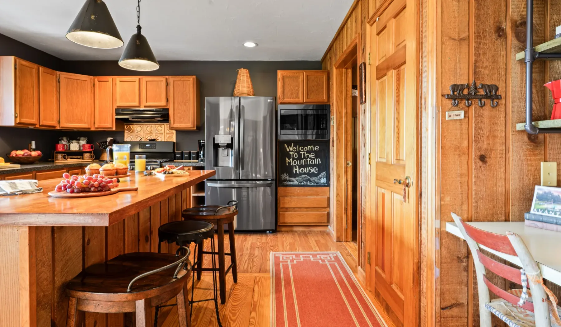 Una cocina revestida de madera con una isla central, electrodomésticos de acero inoxidable y un comedor contiguo.