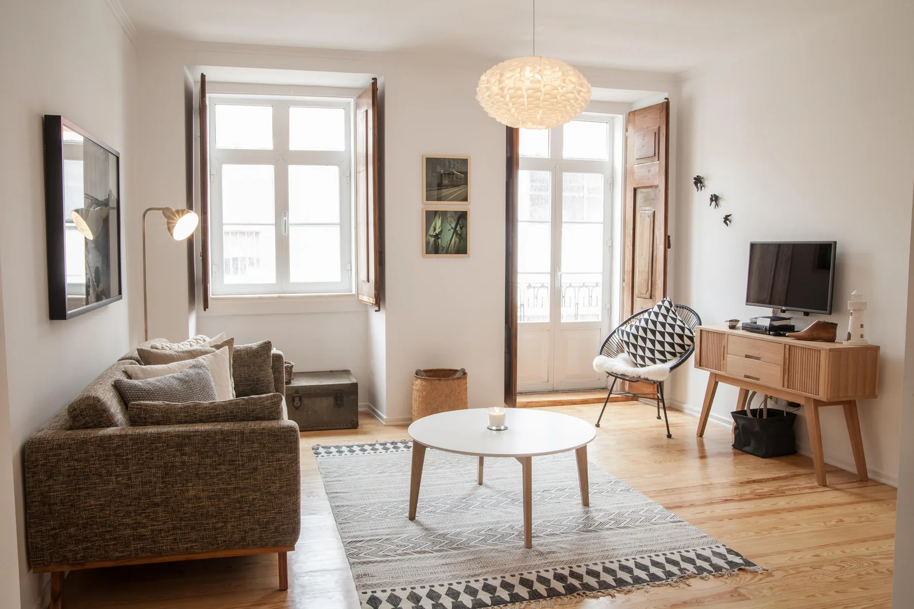 A bright living room with seating, a coffee table, and tall windows.