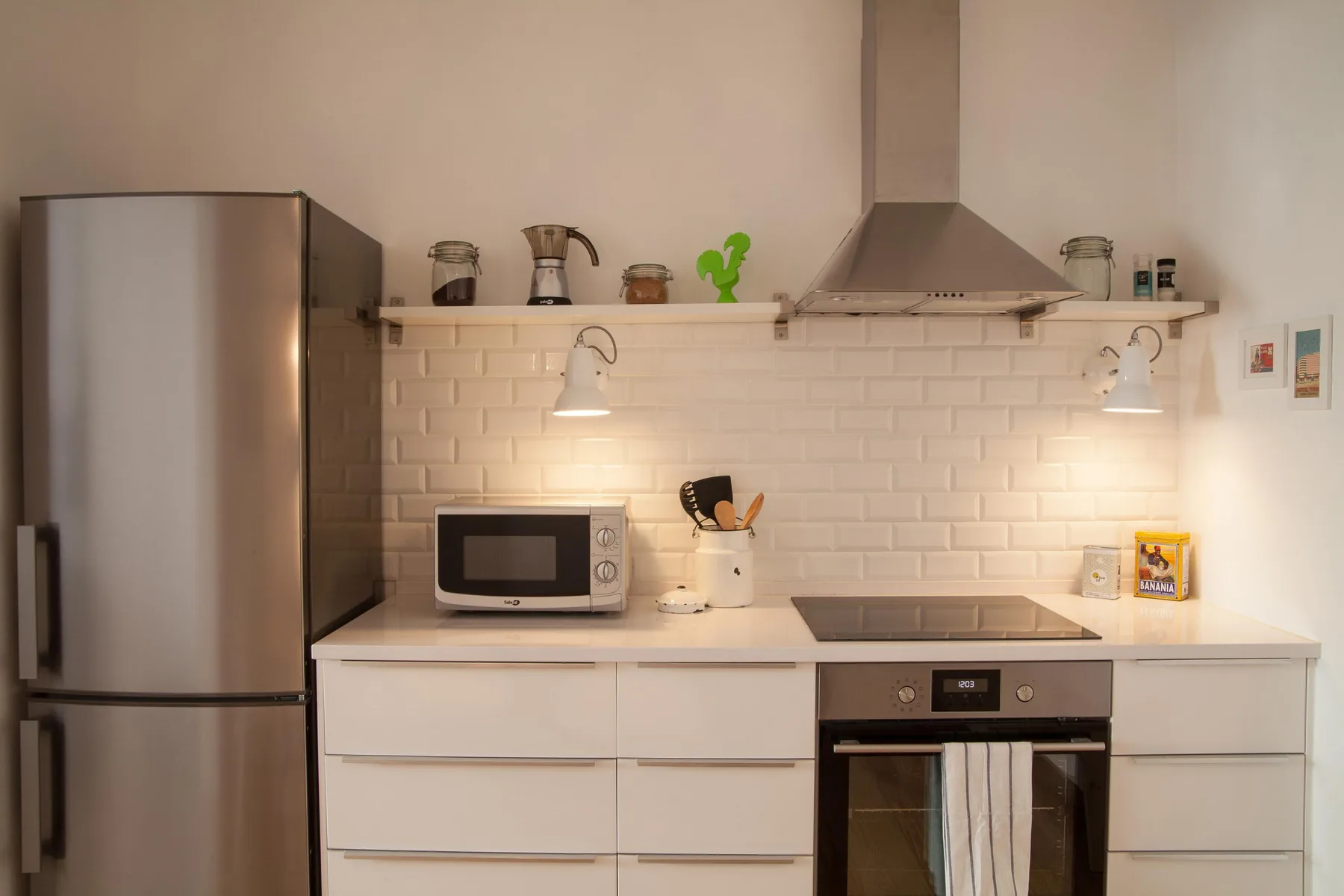 A kitchen with white cabinets, a refrigerator, and a cooktop.