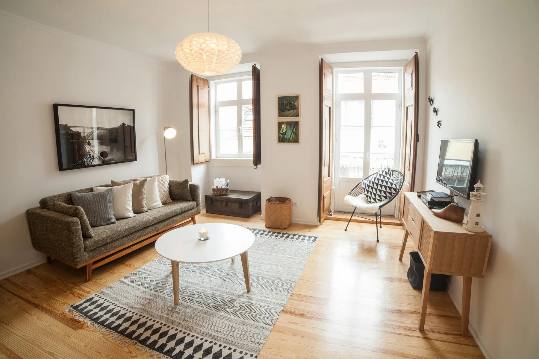 A bright living room with seating, a coffee table, and tall windows.
