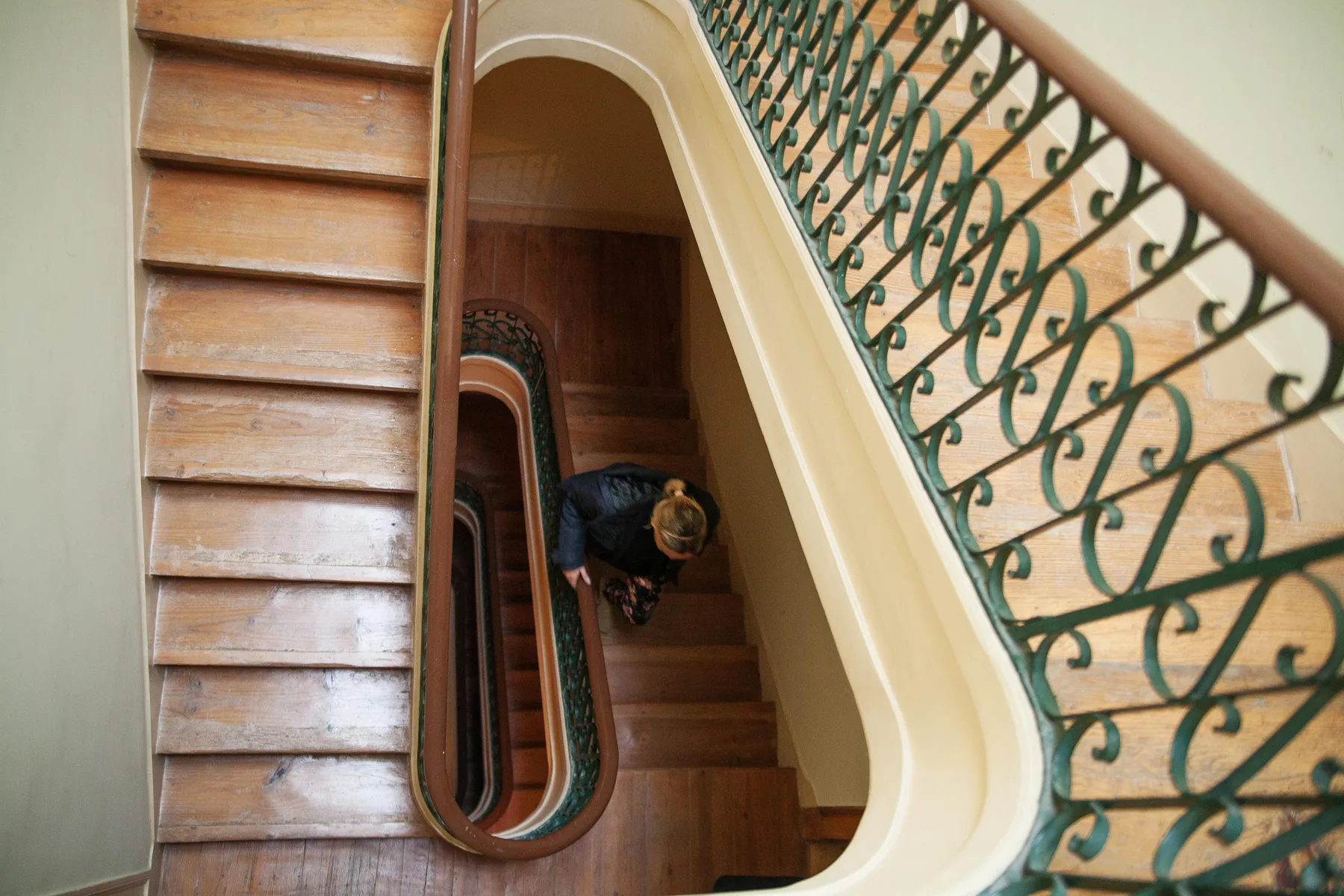A wooden staircase curves around a central opening beneath a decorative railing.
