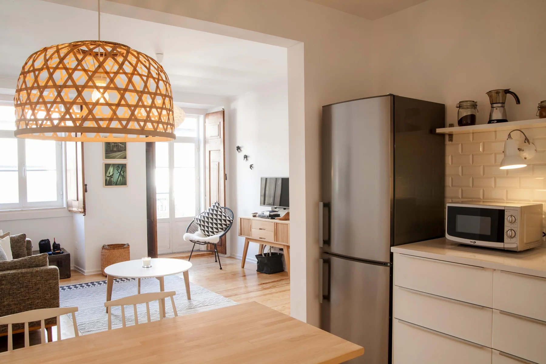 A bright open-plan living area and kitchen with a dining table and pendant lamp.
