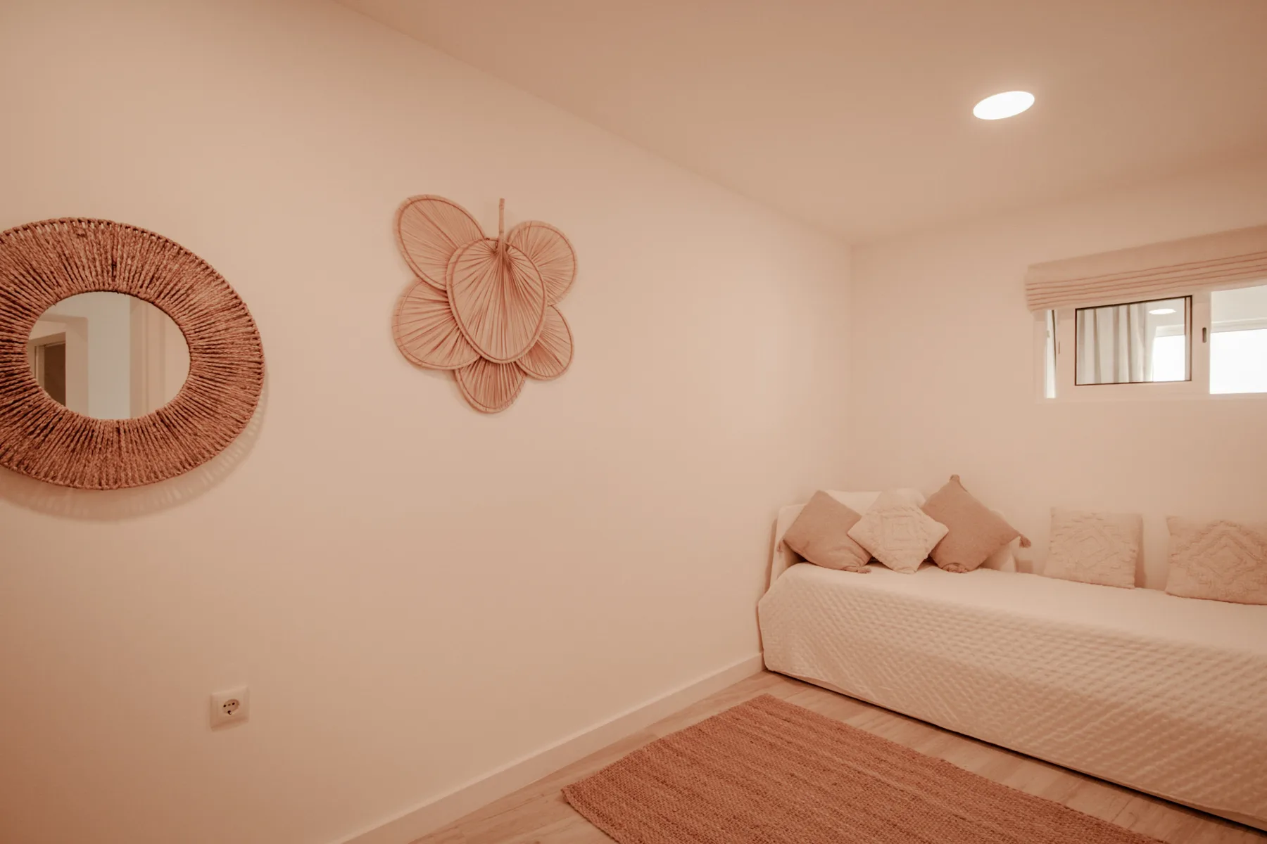 Un dormitorio con una cama baja, adornos tejidos en la pared y una alfombra.