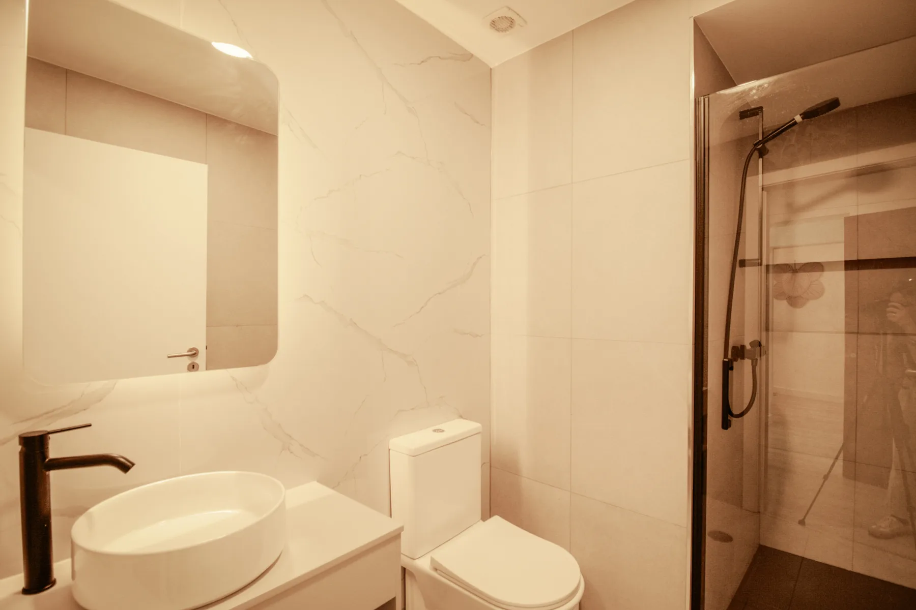 Un baño con lavabo sobre encimera y ducha de cristal.