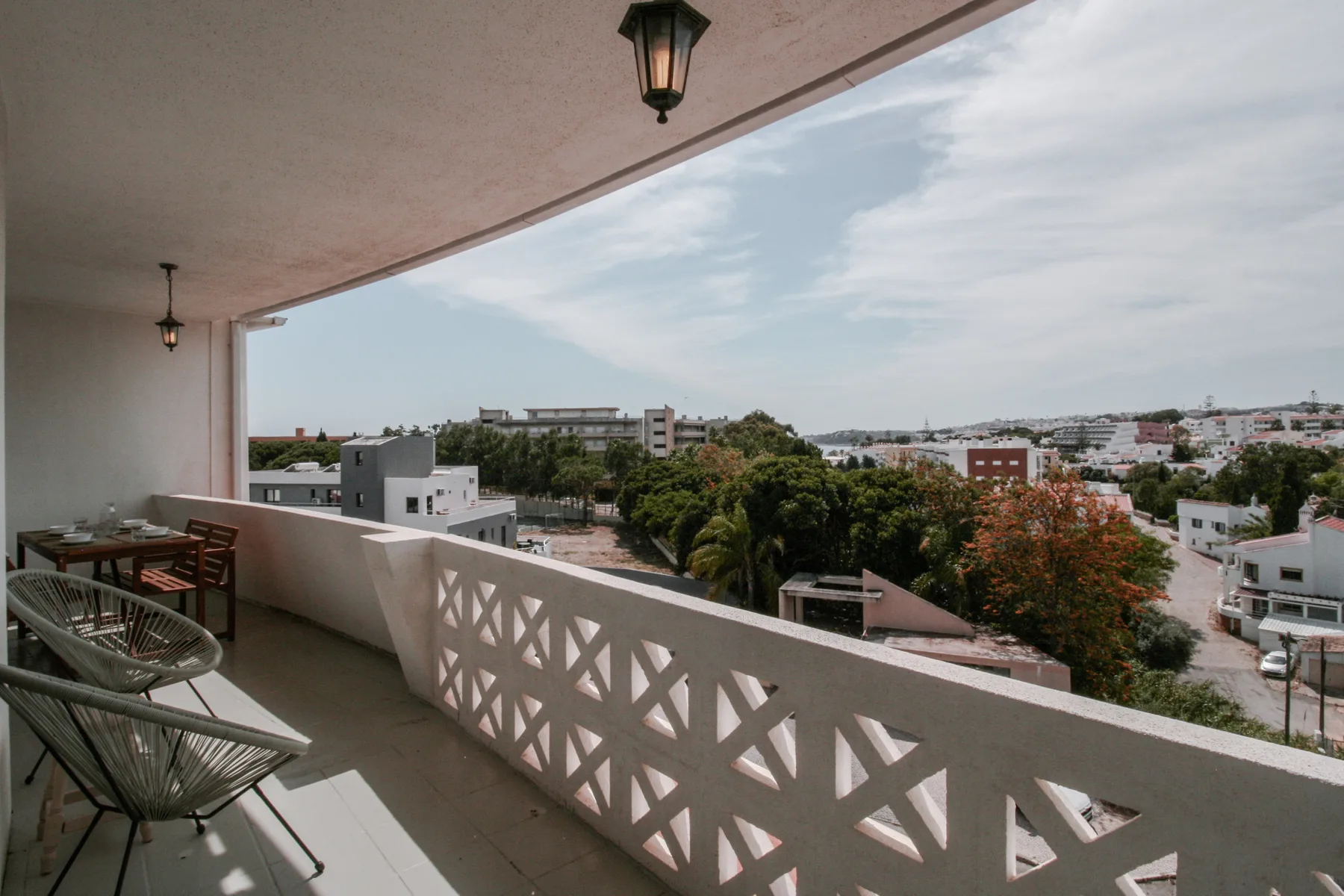 Un balcón cubierto con asientos ofrece vistas de edificios y árboles cercanos.