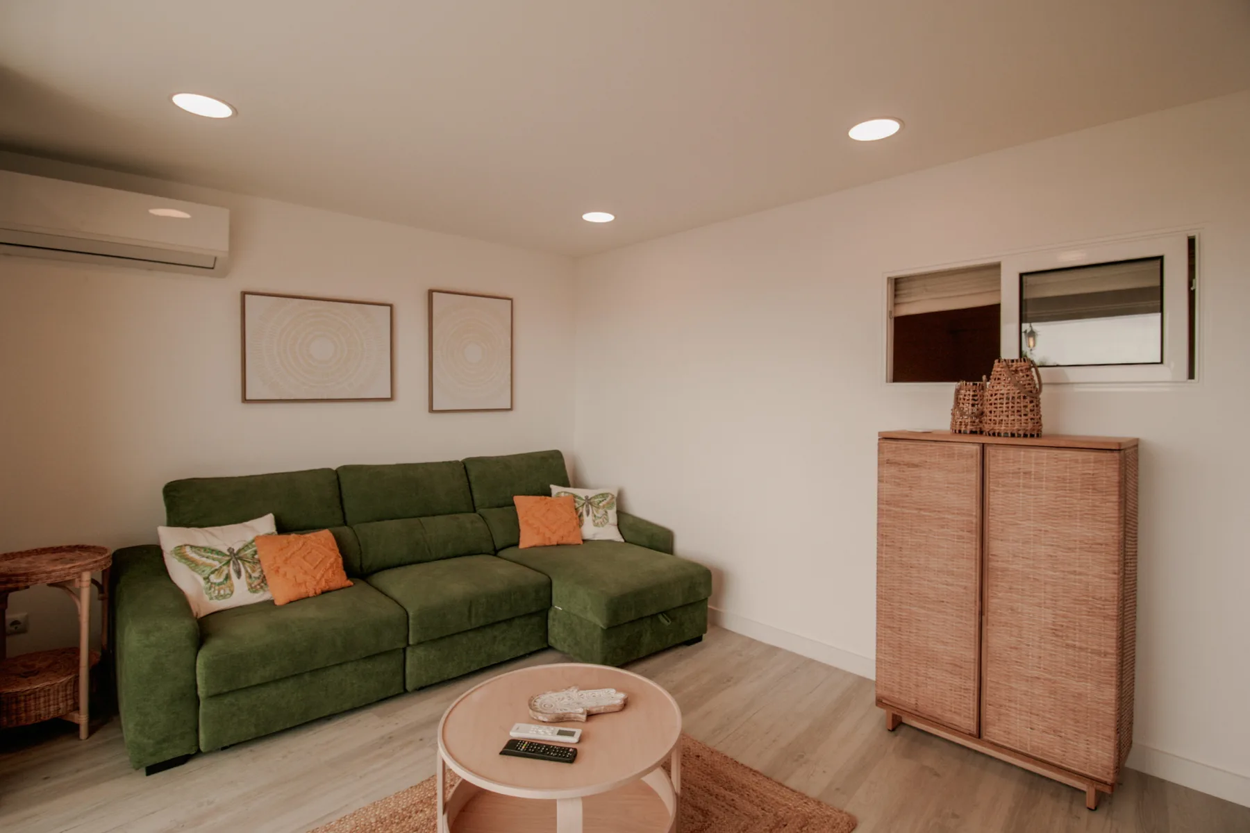Una sala de estar con asientos verdes, una mesa de centro redonda y cuadros en la pared.