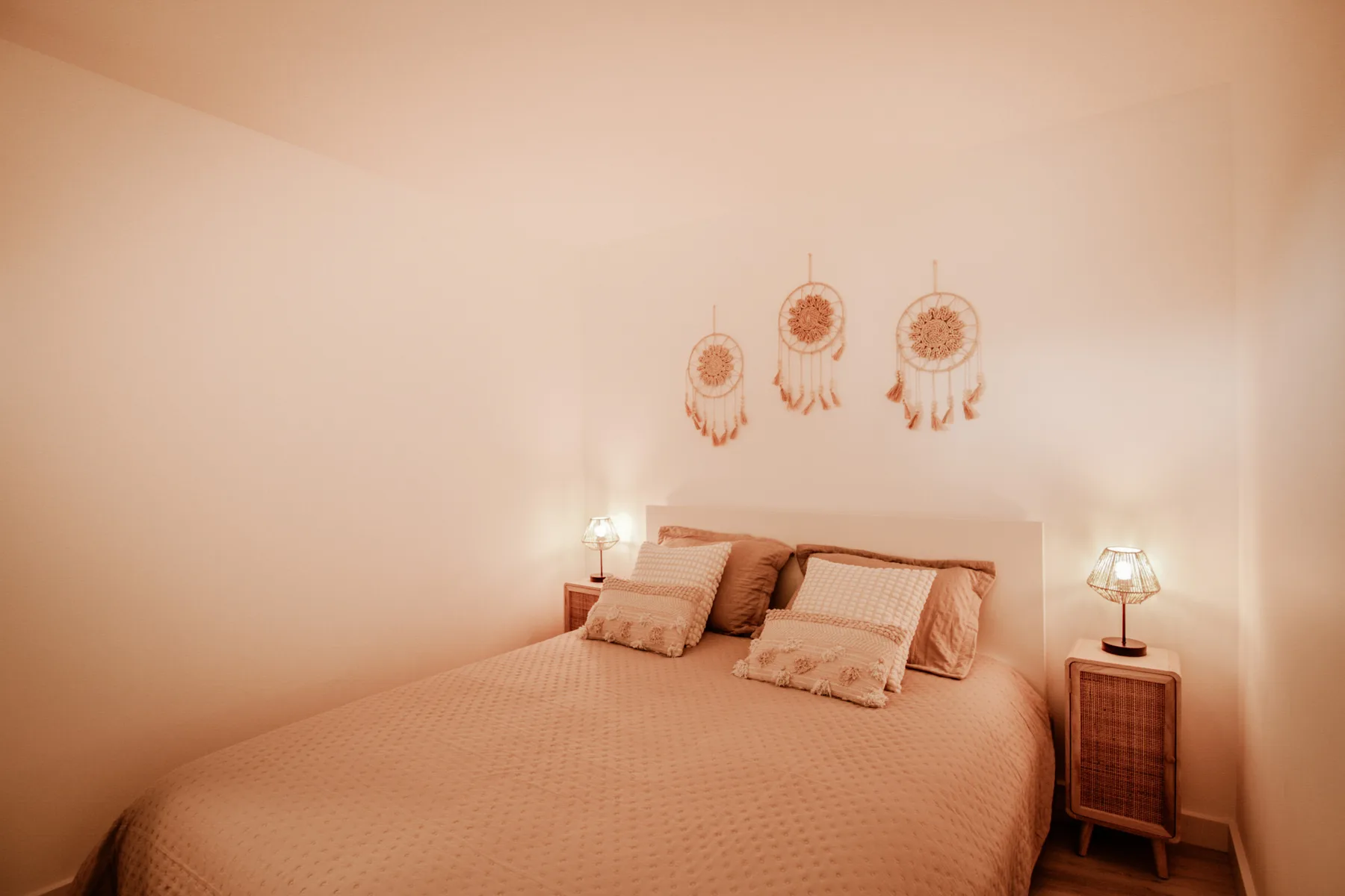 Un dormitorio con una cama, adornos en la pared y lámparas de noche.