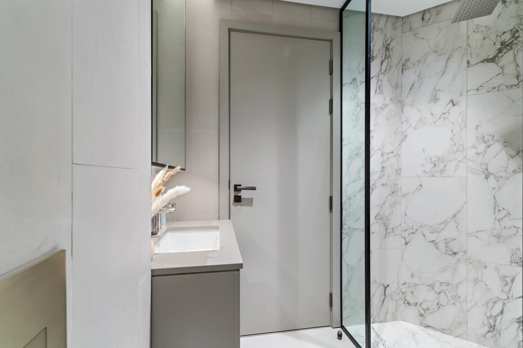 Un baño moderno con un tocador junto a una ducha de vidrio.