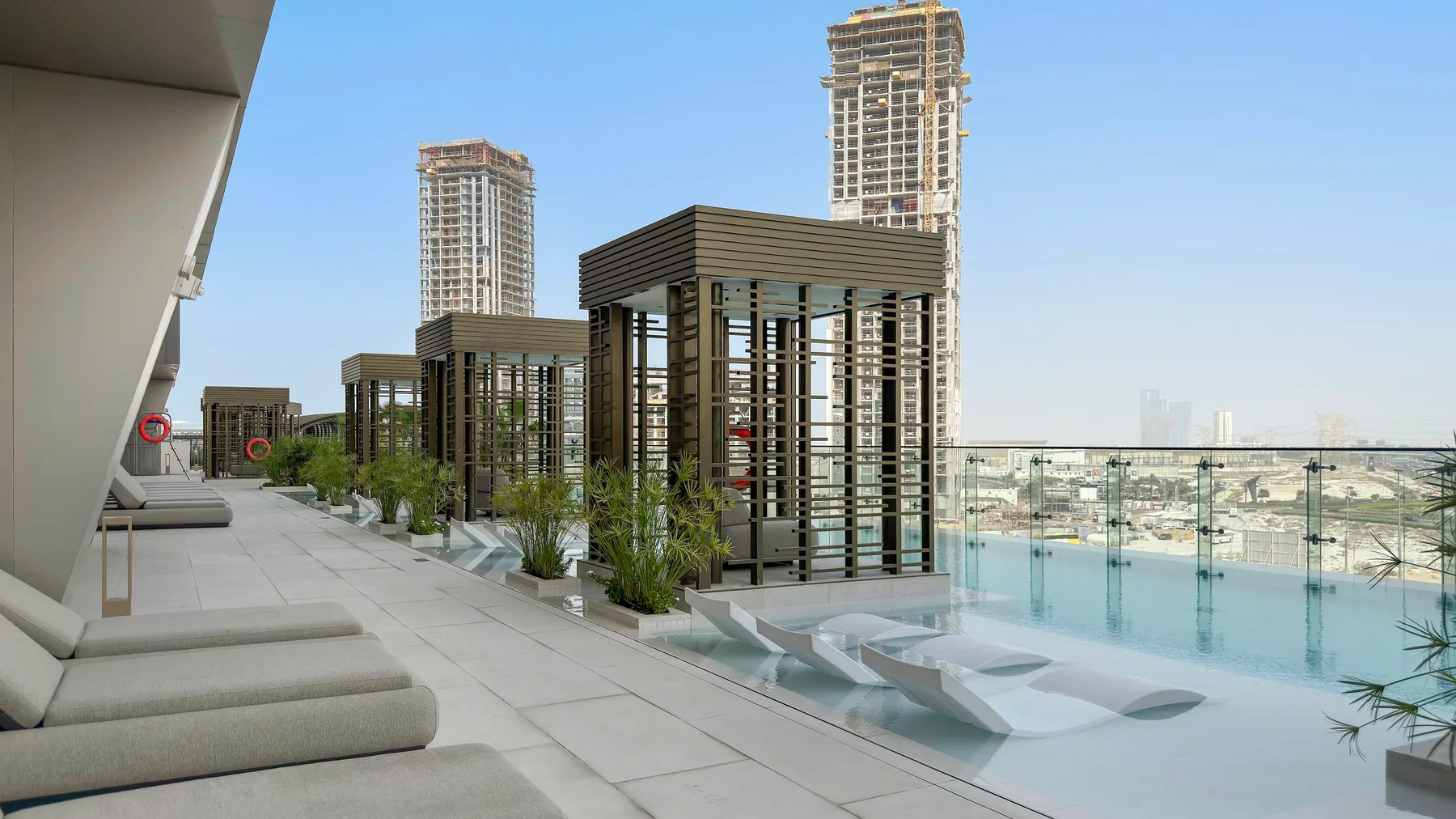 Una terraza en la azotea con asientos, plantas y piscina ofrece vistas de la ciudad.