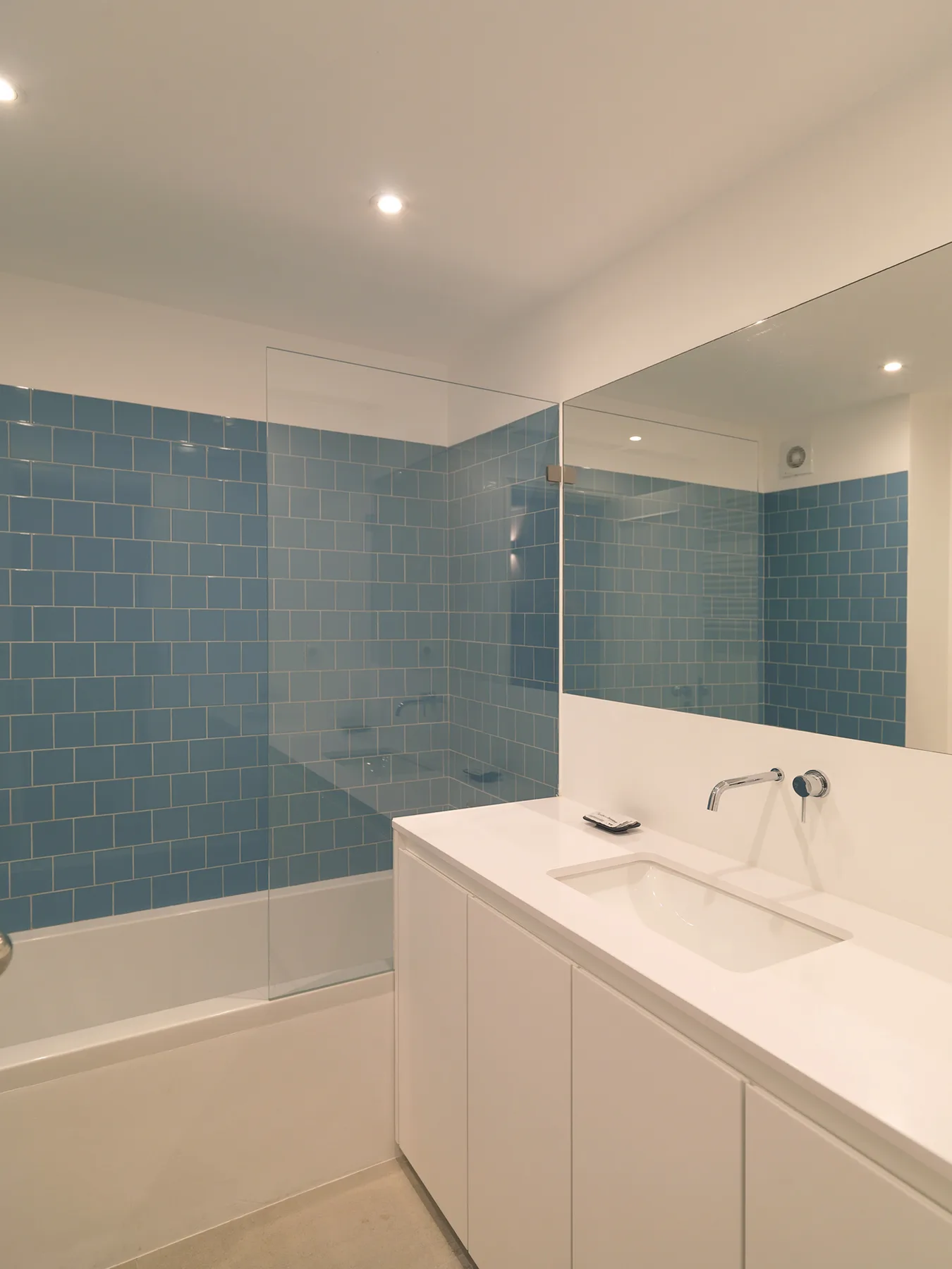 A bathroom with blue tiled walls, a bathtub, and a sink.