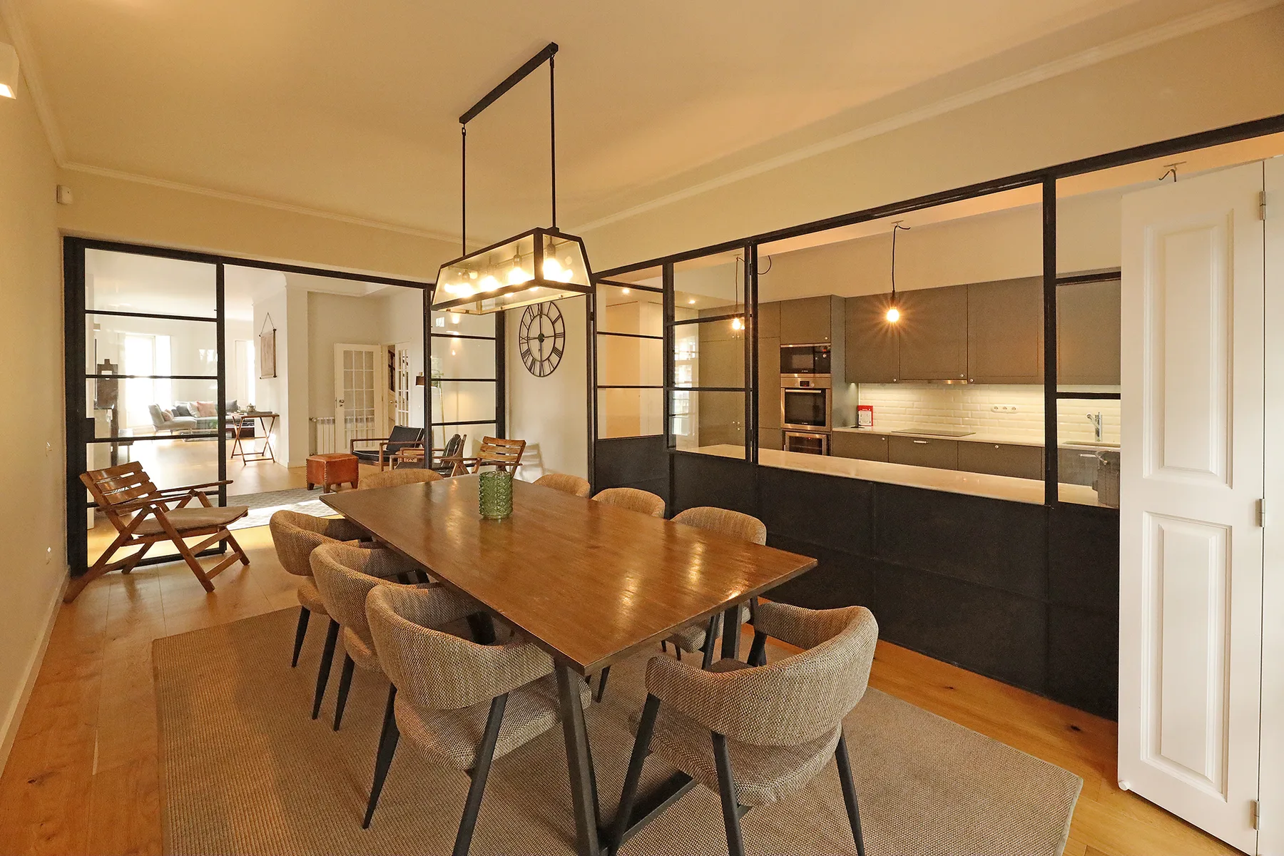 A dining area with a long table and seating beside an open kitchen.