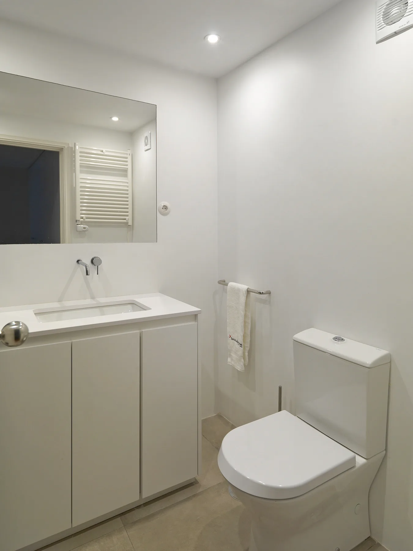 A bright bathroom with a sink, mirror, and toilet.
