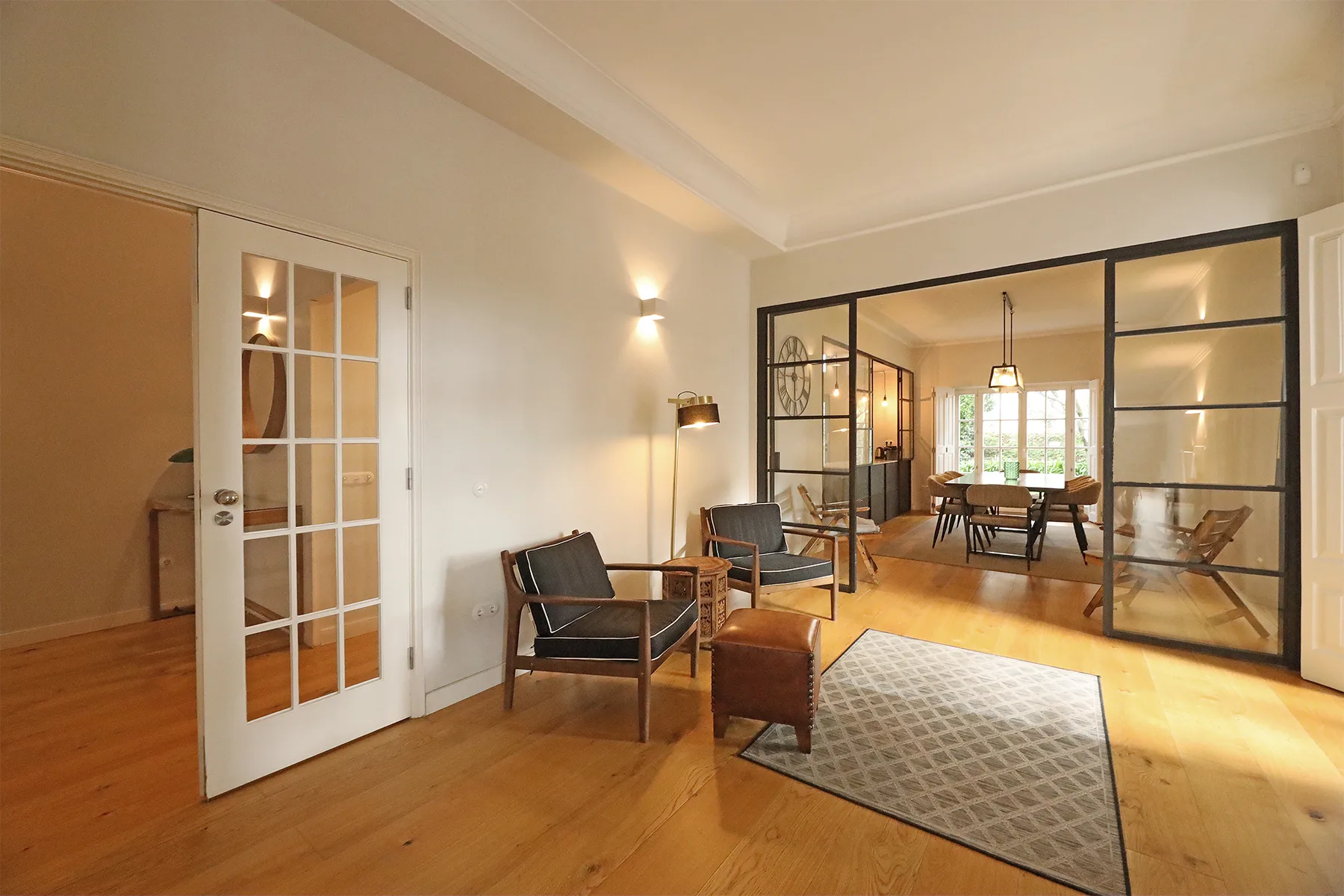 A bright living room with seating and glass doors opening onto a dining area.