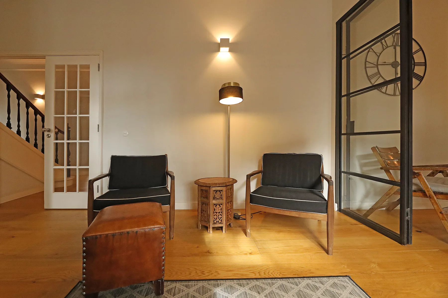 A sitting area with two armchairs and a small table beside a staircase.